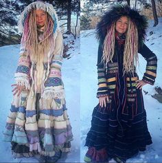 two women dressed in long dresses standing on snow covered ground, one with dreadlocks