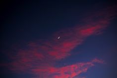 the sun is setting and there is a crescent moon in the sky with pink clouds