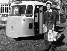 an old photo of a man standing in front of a bus that is parked on the grass