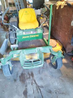 a green lawn mower sitting in a garage