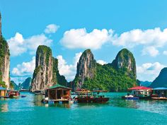 many small boats floating in the water near mountains