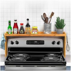 an oven with several cooking utensils on the shelf above it, and various condiments