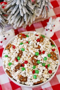 a white bowl filled with popcorn and pretzels on top of a checkered tablecloth