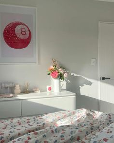 a bedroom with a bed, dresser and flowers in vases on the side table