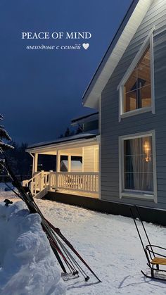 a house with snow on the ground and skis in front of it at night