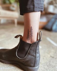 a woman's foot with a small pine tree tattoo on the side of her ankle