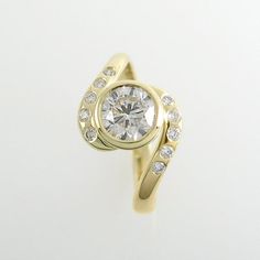 a yellow gold ring with a round diamond surrounded by small white and clear stones, on a plain surface