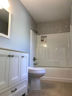 a white toilet sitting in a bathroom next to a bath tub and shower stall under a mirror