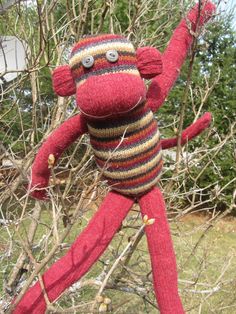 a red stuffed monkey sitting on top of a tree