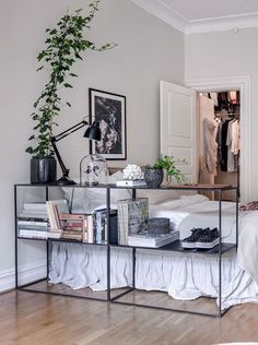 a bedroom with a bed, plant and pictures hanging on the wall above it's headboard