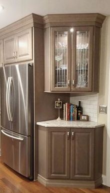 a kitchen with wooden floors and cabinets in the corner, along with a stainless steel refrigerator