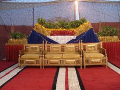 an elaborately decorated stage with gold and blue cloths on the floor, set up for a wedding ceremony