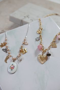 This charm necklace is so sweet and perfect, we can't even handle it. Features mostly vintage mixed-metal charms, hanging on pearls and sterling silver curb chain - to give it just a touch of edginess. 7 charms hang from a strand of sterling freshwater pearls, with a pinkish hue: gold plated vintage teddy bear stainless vintage western hat gold plated cowgirl boot enameled, hand-painted rose charm from the 1960s in center silver plated vintage angel charm gold plated vintage butterfly charm enam Vintage Gold Sterling Silver Necklaces, Whimsical Pendant Charm Necklaces, Metal Charm Necklace With Pearl Pendant, Whimsical Charm Necklaces For Jewelry Making, Whimsical Charm Necklaces With Dangle Charms, Dainty Charm Necklace With Dangling Charms, Whimsical Dangle Charm Necklaces For Jewelry Making, Whimsical White Charm Necklaces, Whimsical Gold Vintage Charm Necklace