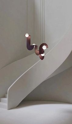 three circular lights hanging from the side of a spiral staircase in a room with white walls and flooring