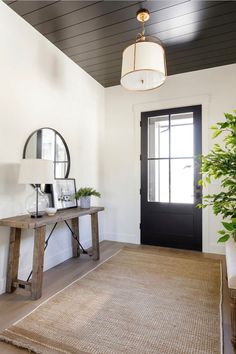 a living room with a rug, mirror and plant on the floor in front of it