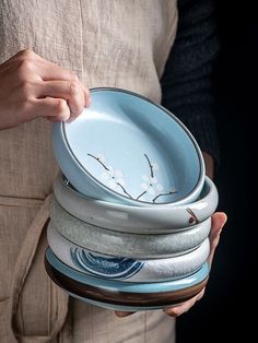 a person holding a stack of bowls in their hands