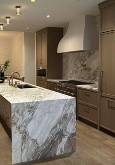 a large kitchen with marble counter tops and wooden cabinets, along with stainless steel appliances