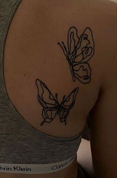 the back of a woman's shoulder with two butterflies on it