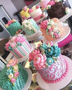 many cakes are stacked on top of each other and decorated with colorful flowers in the center