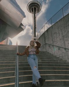 a woman sitting on some stairs next to the space needle