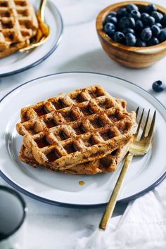 two waffles sitting on top of a white plate with blueberries in the background