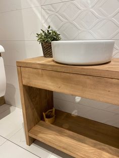 a white bowl sitting on top of a wooden counter next to a toilet paper dispenser