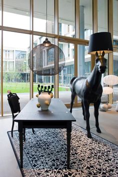 a horse statue stands in the middle of a living room with large windows and an area rug