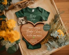 a baby's first birthday gift with a heart shaped wooden plaque and flowers on the floor