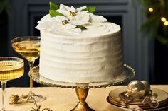 a white cake sitting on top of a table next to two wine glasses and a plate