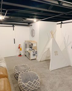 a living room with a teepee tent next to a brown leather couch and white walls