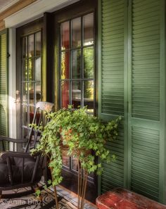 a chair sitting on top of a wooden porch next to a green door and window