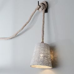 a roped light hanging from the side of a wall next to a lamp shade