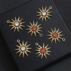 six gold star charms with red and white stones in them sitting on a black surface