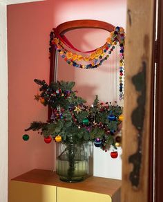 a vase filled with christmas decorations on top of a wooden dresser next to a mirror