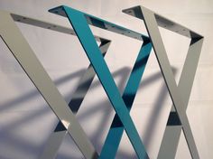 an abstract sculpture is displayed against a white wall with blue and silver strips on it