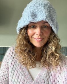 a woman with curly hair wearing a knitted hat