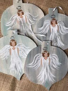 three angel ornaments are sitting on the floor next to some burlocked fabric