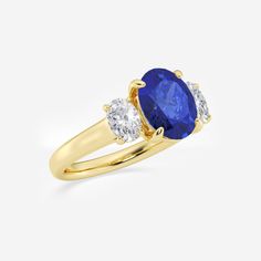 a yellow gold ring with an oval blue sapphire and three diamonds