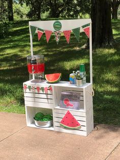 an outdoor stand with watermelon slices and other items on it's sides