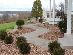 a stone path leading to a house next to a body of water in the background