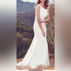 a woman in a white wedding dress posing for a photo with mountains in the background