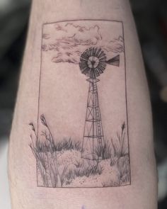 a black and white photo of a windmill on the side of a man's leg