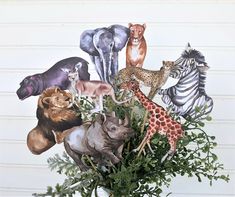 a vase filled with lots of different types of wild animals on top of green leaves