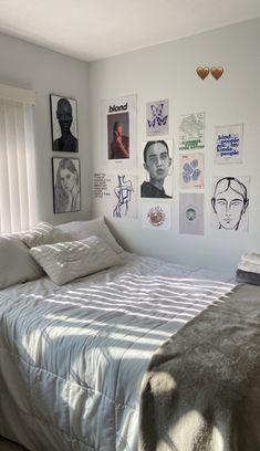 a bed sitting in a bedroom next to a window with pictures on the wall above it