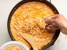 a person scooping cheese out of a skillet