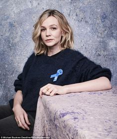 a woman sitting at a table with a blue ribbon on her sweater