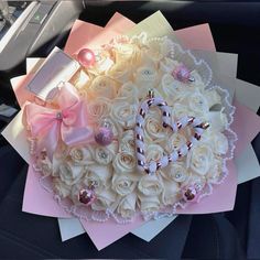 a bouquet of white roses and pink ribbon in the back seat of a car, decorated with candy canes