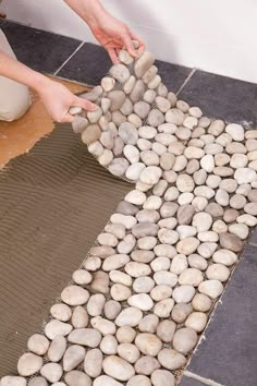 a person placing rocks on top of a tile floor