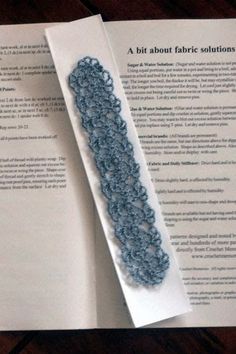 an open book with a crochet pattern on it next to a piece of paper