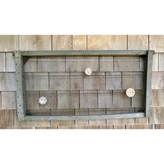 an old metal grate mounted to the side of a wooden wall with three knobs